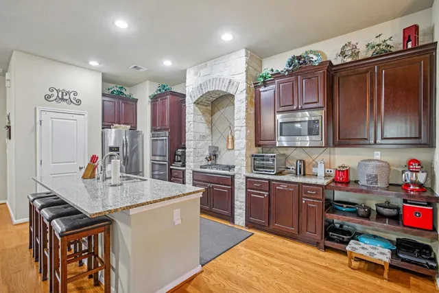 a kitchen with stainless steel appliances granite countertop a sink dishwasher stove and refrigerator with wooden cabinets