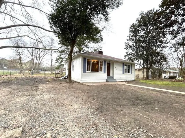a view of a house with a yard and large trees
