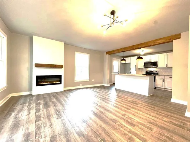 a view of an empty room with a window and kitchen view