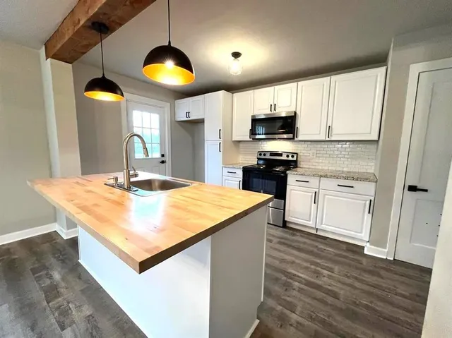 a kitchen with stainless steel appliances granite countertop a stove a sink and a microwave