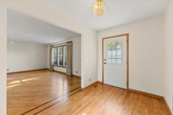 a view of an empty room with window and wooden floor