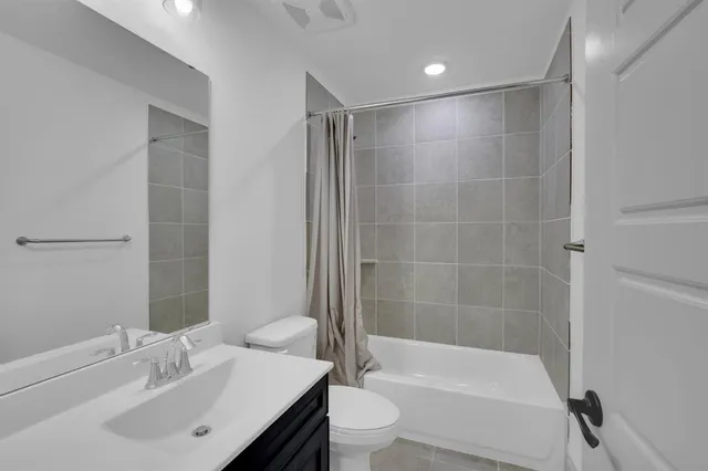 a bathroom with a bathtub shower sink vanity and toilet