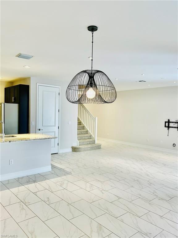 7841 Bristol Circle Naples, FL 34120 - Photo 11 of 31 Unfurnished living room with hanging lights and light marble finish floors