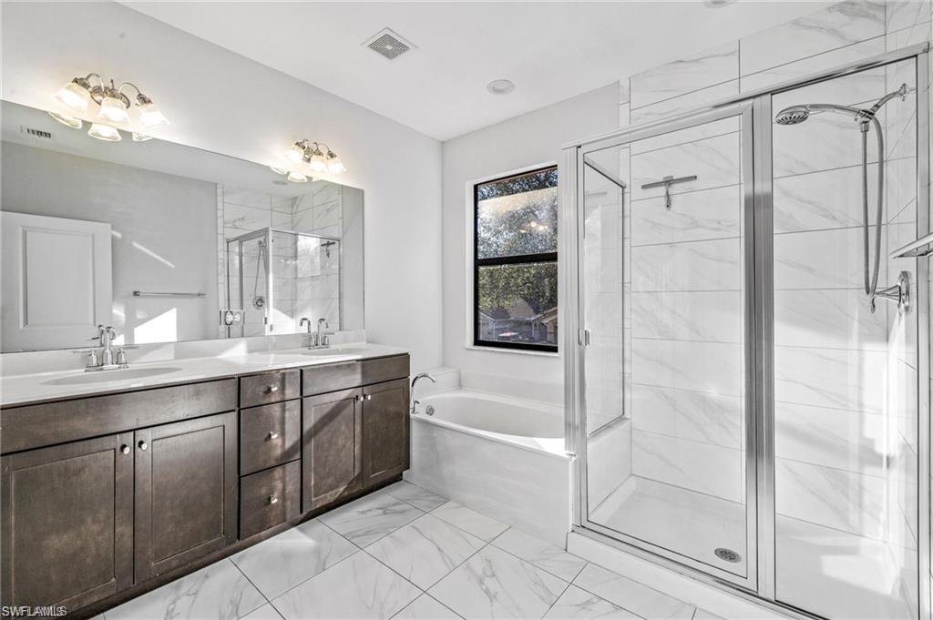 7841 Bristol Circle Naples, FL 34120 - Photo 16 of 31 Full bath featuring double vanity, a stall shower, a garden tub, and light marble finish floors