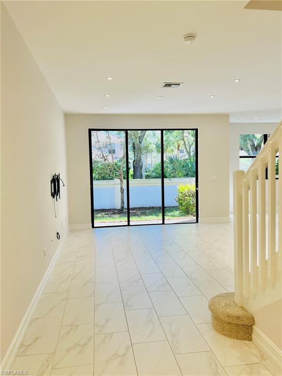 7841 Bristol Circle Naples, FL 34120 - Photo 4 of 31 Empty room featuring healthy amount of natural light and light marble finish flooring