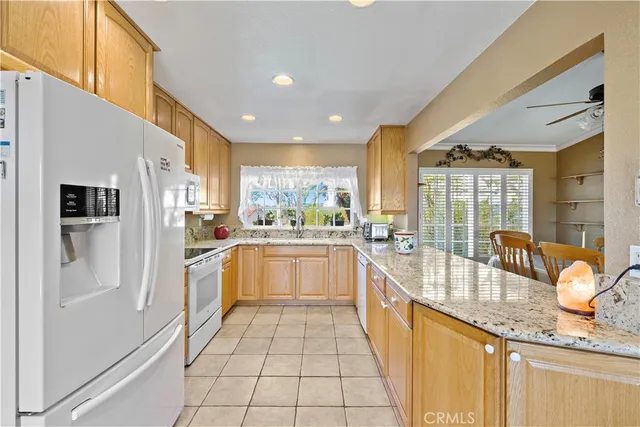a large white kitchen with granite countertop a large window and stainless steel appliances