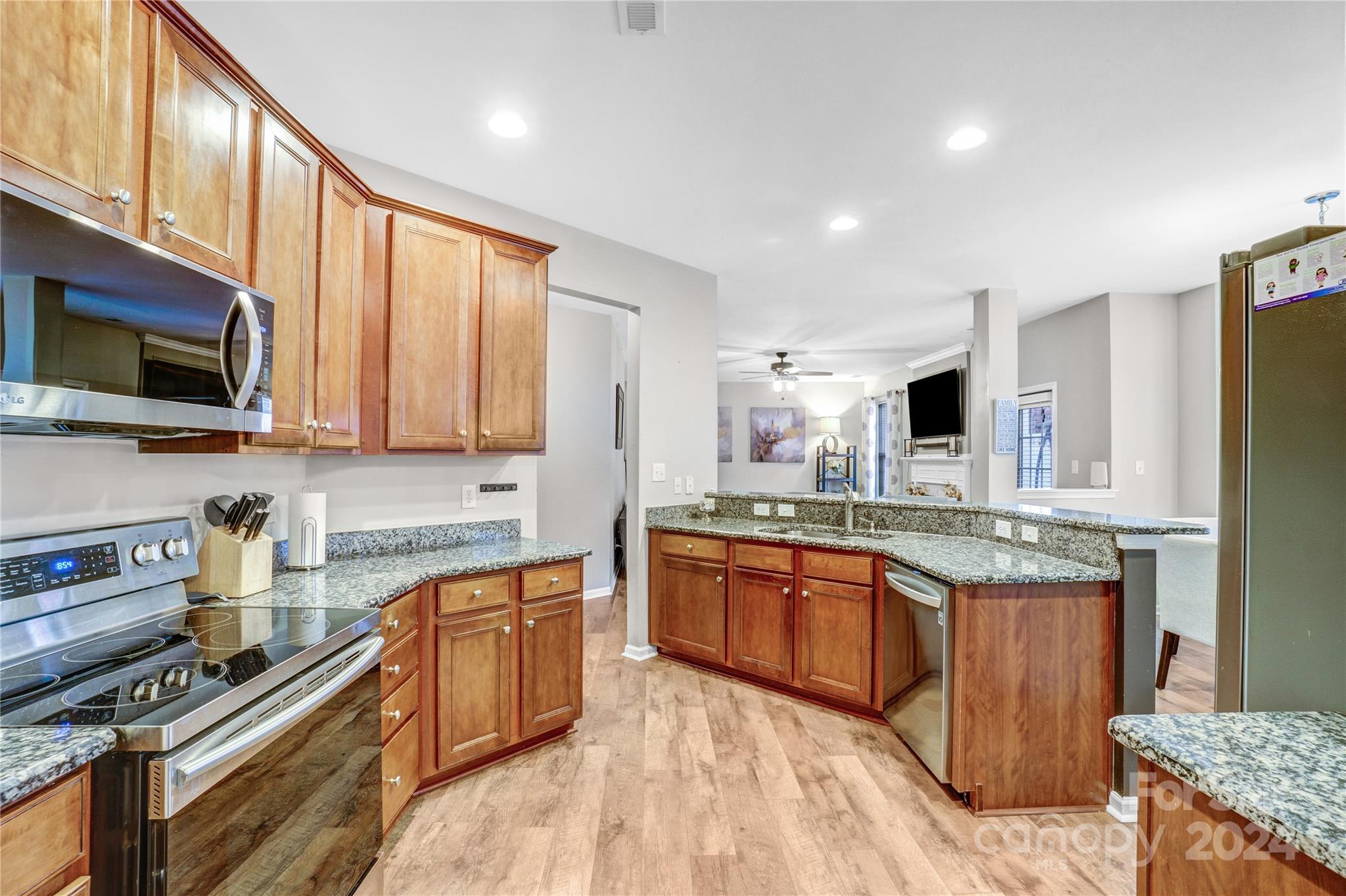 14432 Whistling Swan Road Charlotte, NC 28278 - Photo 7 of 28 a large kitchen with stainless steel appliances granite countertop a stove top oven a sink dishwasher and wooden cabinets with wooden floor