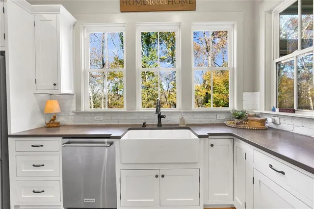 a kitchen with stainless steel appliances granite countertop white cabinets and a stove a oven with white countertops