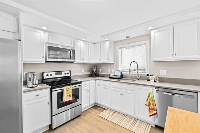 a kitchen with stainless steel appliances granite countertop a sink and white cabinets