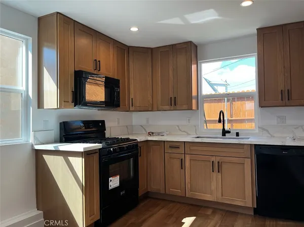 a kitchen with stainless steel appliances a sink a stove a microwave cabinets and a window