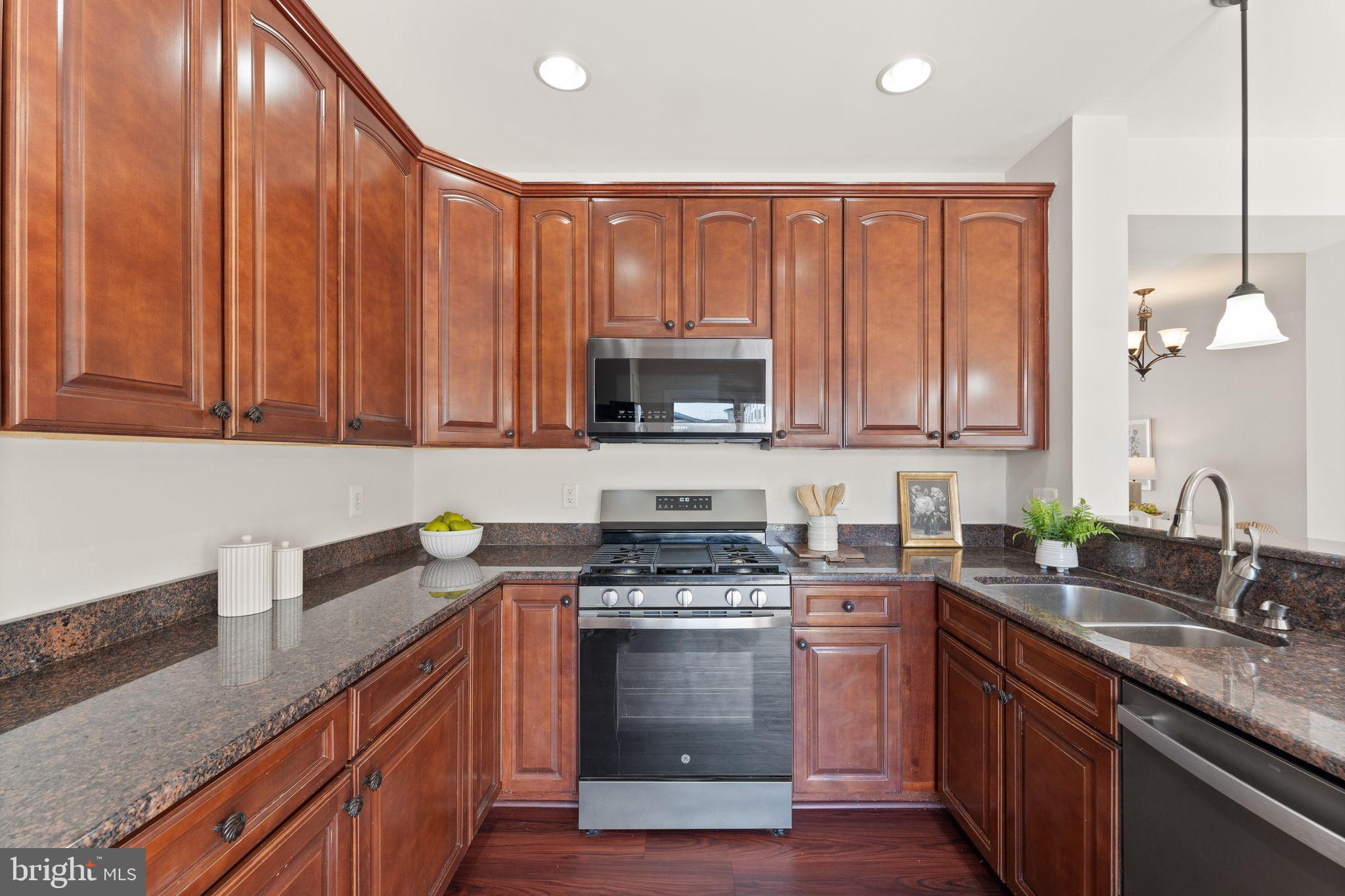 6072 Wicker Lane, Unit 160 Centreville, VA 20121 - Photo 23 of 58 a kitchen with granite countertop a stove top oven microwave and cabinets