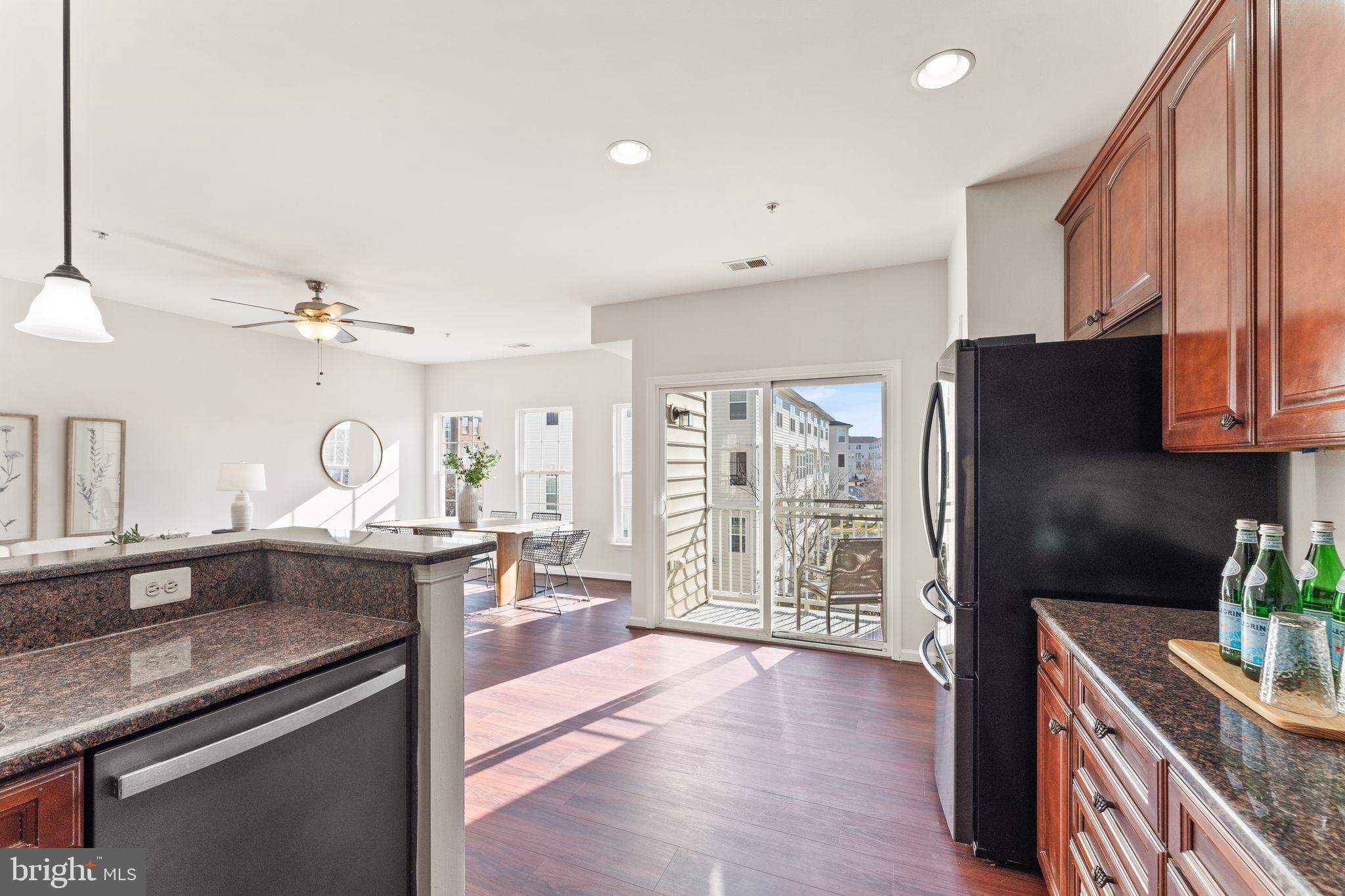 6072 Wicker Lane, Unit 160 Centreville, VA 20121 - Photo 25 of 58 a kitchen with stainless steel appliances granite countertop a refrigerator a sink dishwasher a dining table and chairs with wooden floor