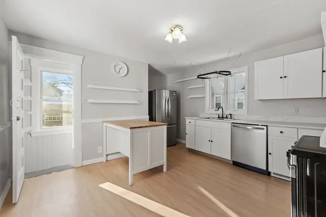 a kitchen with stainless steel appliances white cabinets and wooden floors