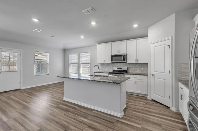 a kitchen with granite countertop white cabinets and wooden floor