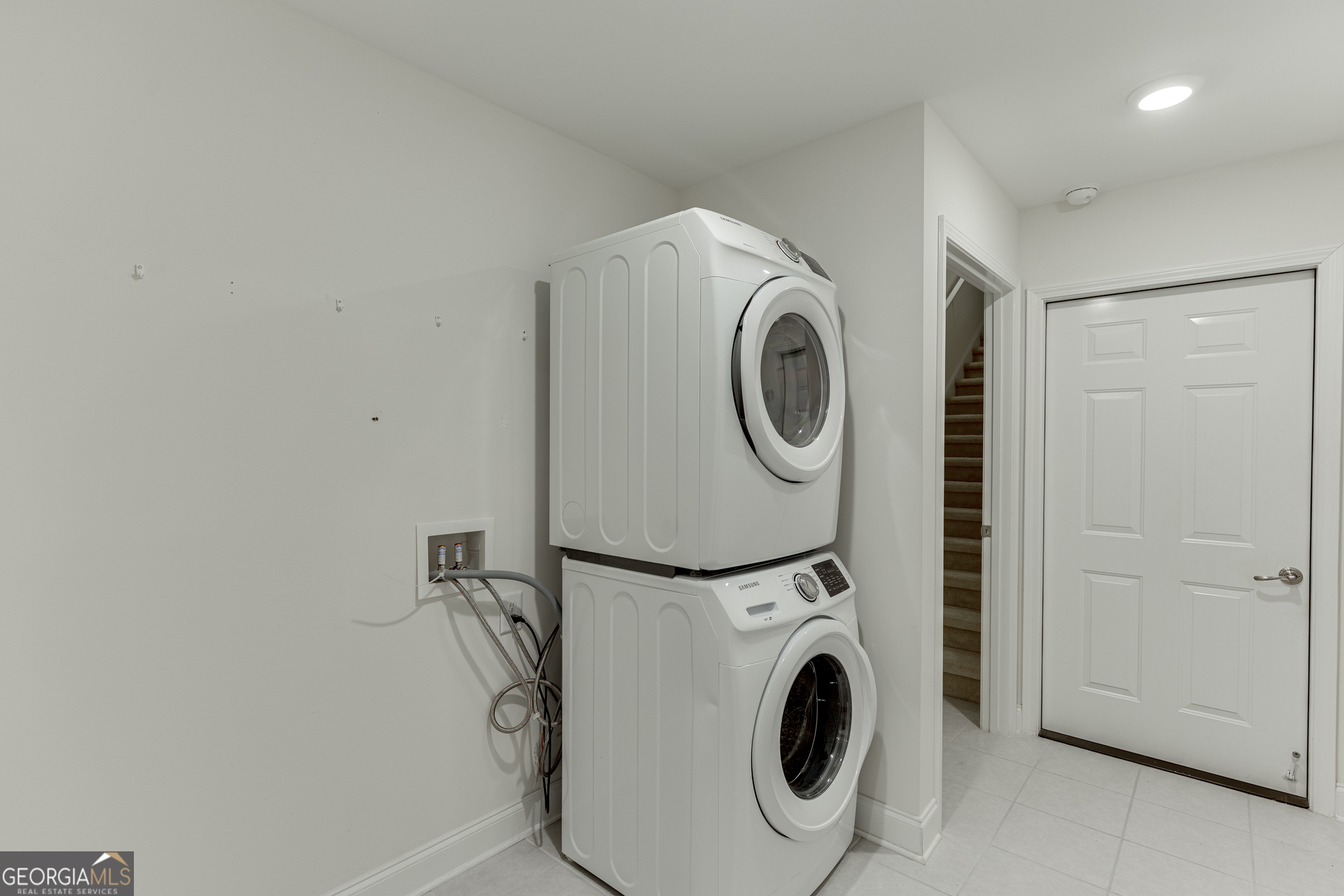 3765 Ridgehurst Drive Buford, GA 30518 - Photo 33 of 44 Laundry room with stacked washer and dryer setup and storage shelving.