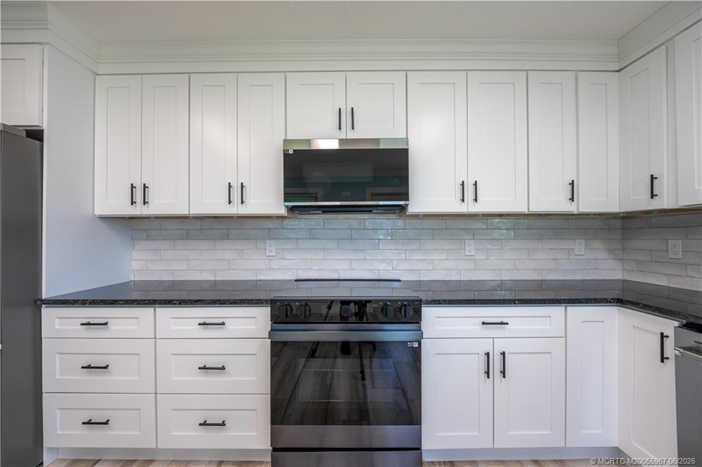 8200 Southwest Springhaven Avenue Indiantown, FL 34956 - Photo 17 of 35 a kitchen with white cabinets and a stove with a sink