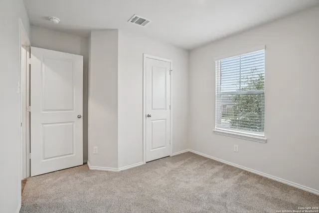 a view of an empty room with closet and a window