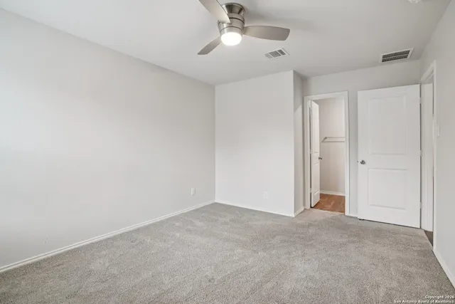 a view of an empty room and chandelier fan