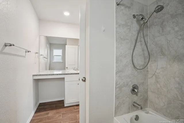 a bathroom with a granite countertop sink a mirror and shower