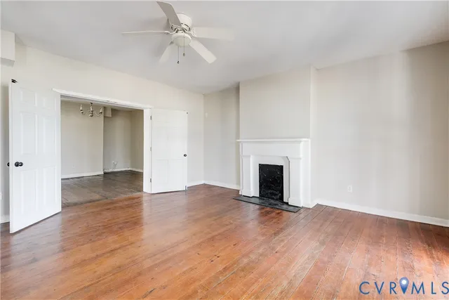 an empty room with wooden floor fireplace and windows