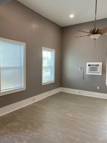 an empty room with windows and fan