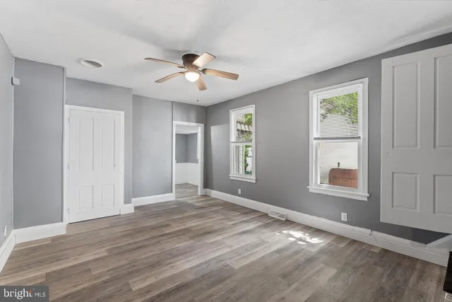 a view of an empty room with a window and wooden floor