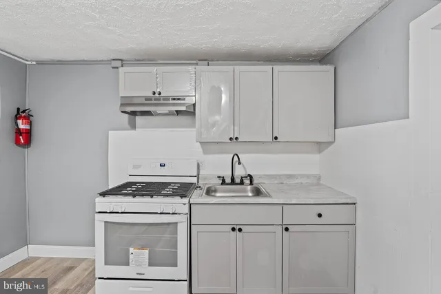 a kitchen with stainless steel appliances granite countertop a stove a sink and a white cabinets