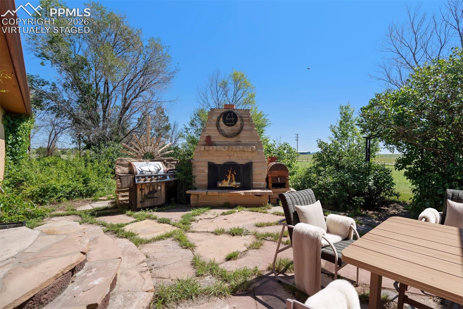 2550 Slocum Road Peyton, CO 80831 - Photo 39 of 50 virtually staged Stone patio featuring an outdoor fireplace with a prominent hearth, a built-in outdoor grill, and irregular flagstone pavers