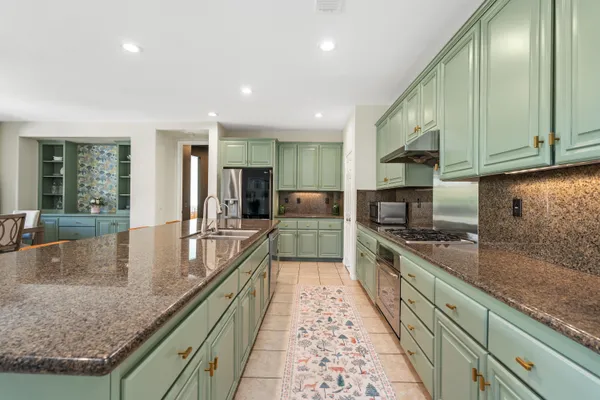 a large kitchen with stainless steel appliances granite countertop a sink a stove and cabinets