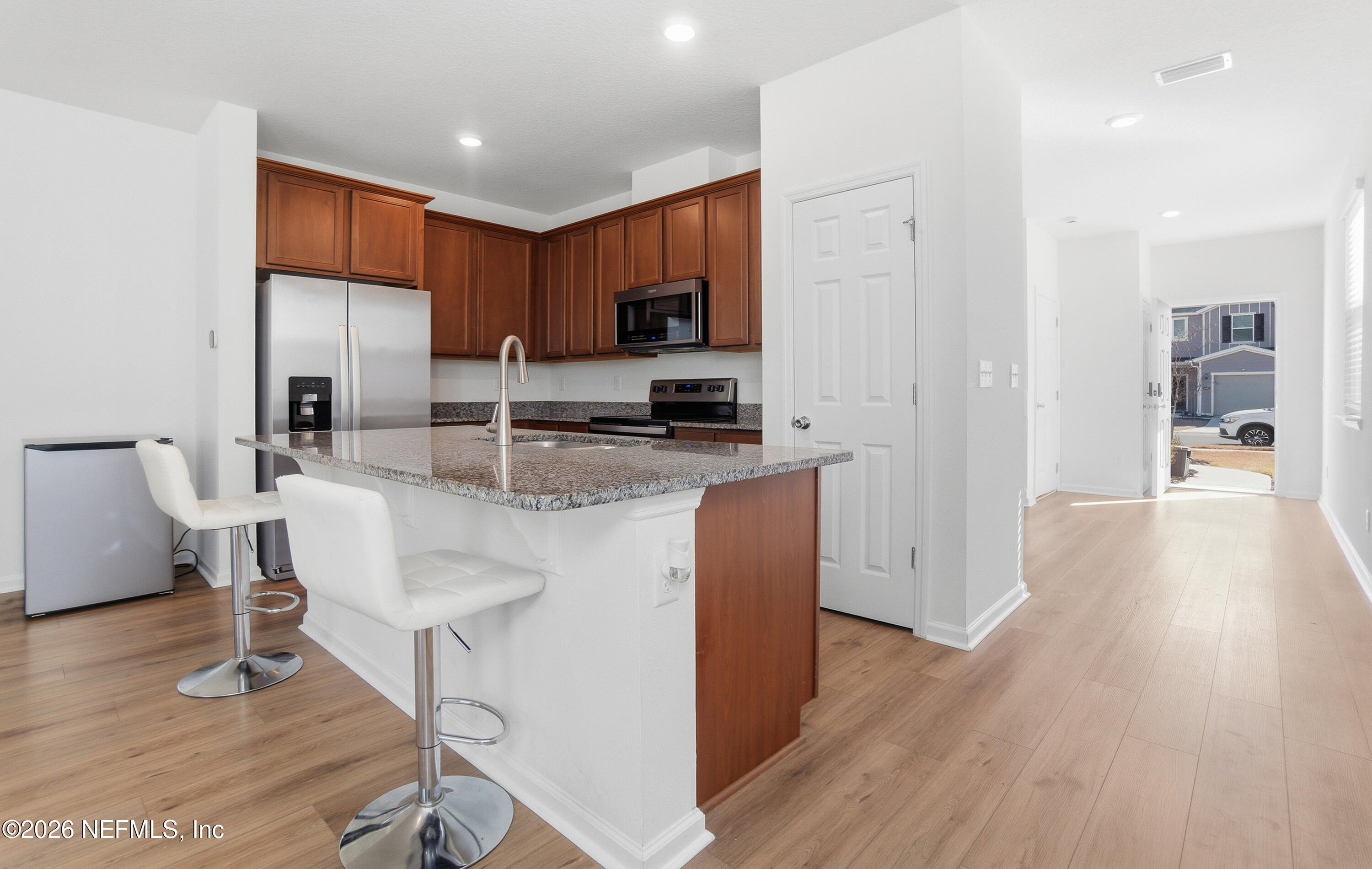 7662 Merchants Way Jacksonville, FL 32222 - Photo 9 of 32 a kitchen with stainless steel appliances granite countertop a microwave a stove a sink dishwasher and a refrigerator with wooden floor