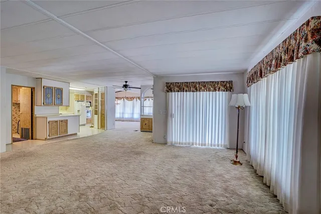 a view of an empty room with window and a ceiling fan