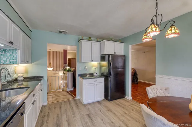 a kitchen with stainless steel appliances granite countertop a refrigerator a sink dishwasher a stove and white countertops with wooden floor