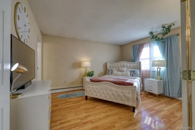 a spacious bedroom with a bed and a flat tv screen on dresser