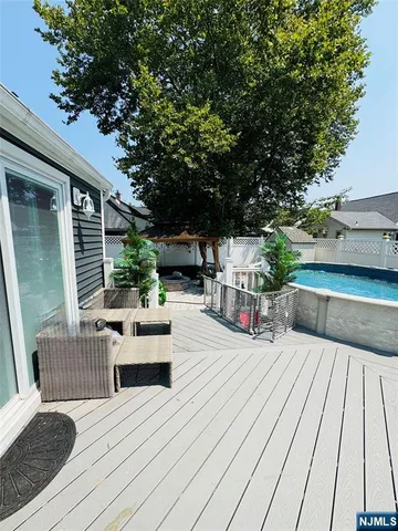 a view of a patio with couches and potted plants with wooden floor and fence