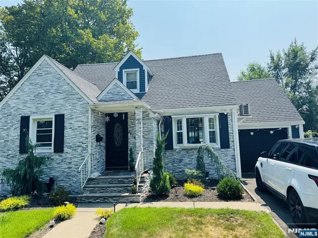 a front view of house with yard and trees in the background
