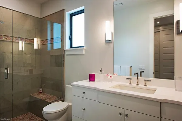 a bathroom with a sink toilet vanity and shower