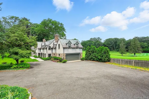a view of a house with a big yard plants and large trees