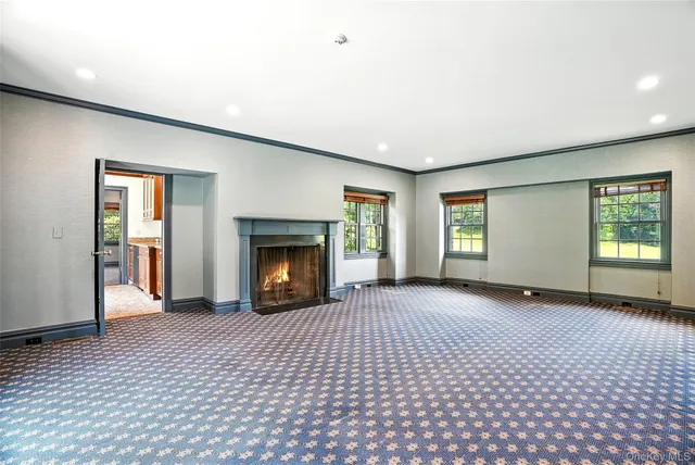 an empty room with windows and fireplace