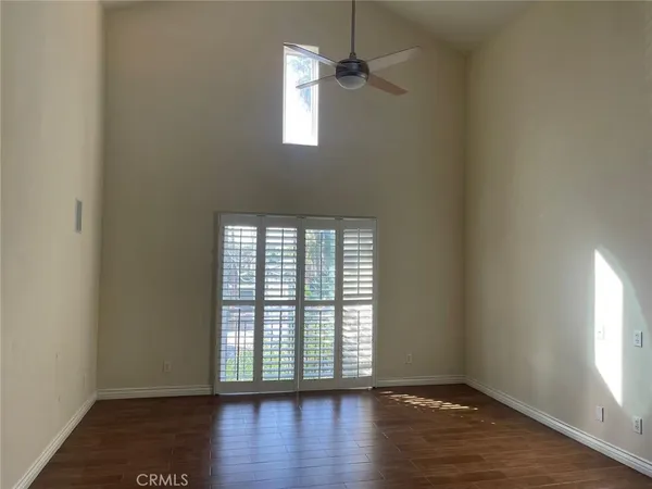 an empty room with wooden floor cabinet and windows