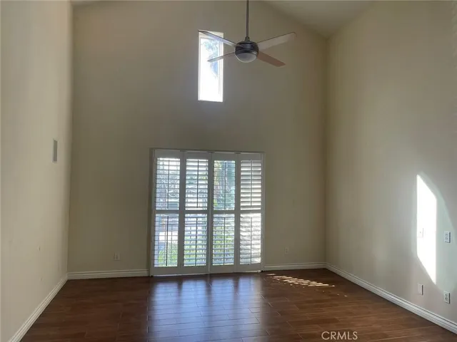 an empty room with wooden floor cabinet and windows