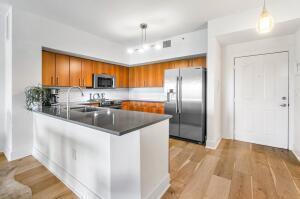 250 Northeast 3rd Avenue, Unit 1510 Delray Beach, FL 33444 - Photo 16 of 50 a kitchen with stainless steel appliances granite countertop a refrigerator a sink a stove a oven a dining table and chairs with wooden floor