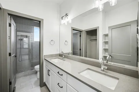 a bathroom with a double vanity sink mirror and shower