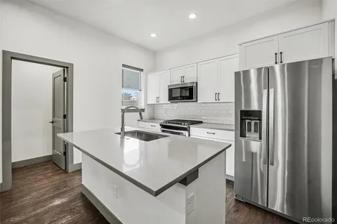 a kitchen with kitchen island a refrigerator stove microwave and sink