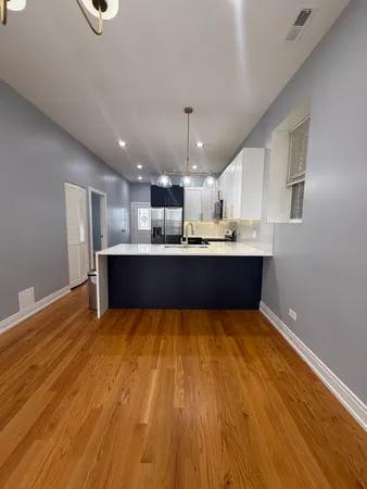 a kitchen with stainless steel appliances kitchen island granite countertop a sink dishwasher and a stove with wooden floor