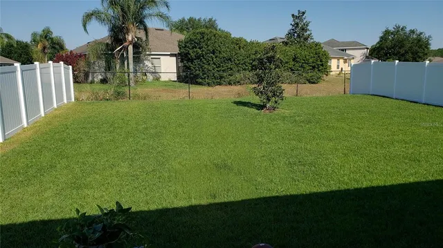 a view of an house with backyard and trees