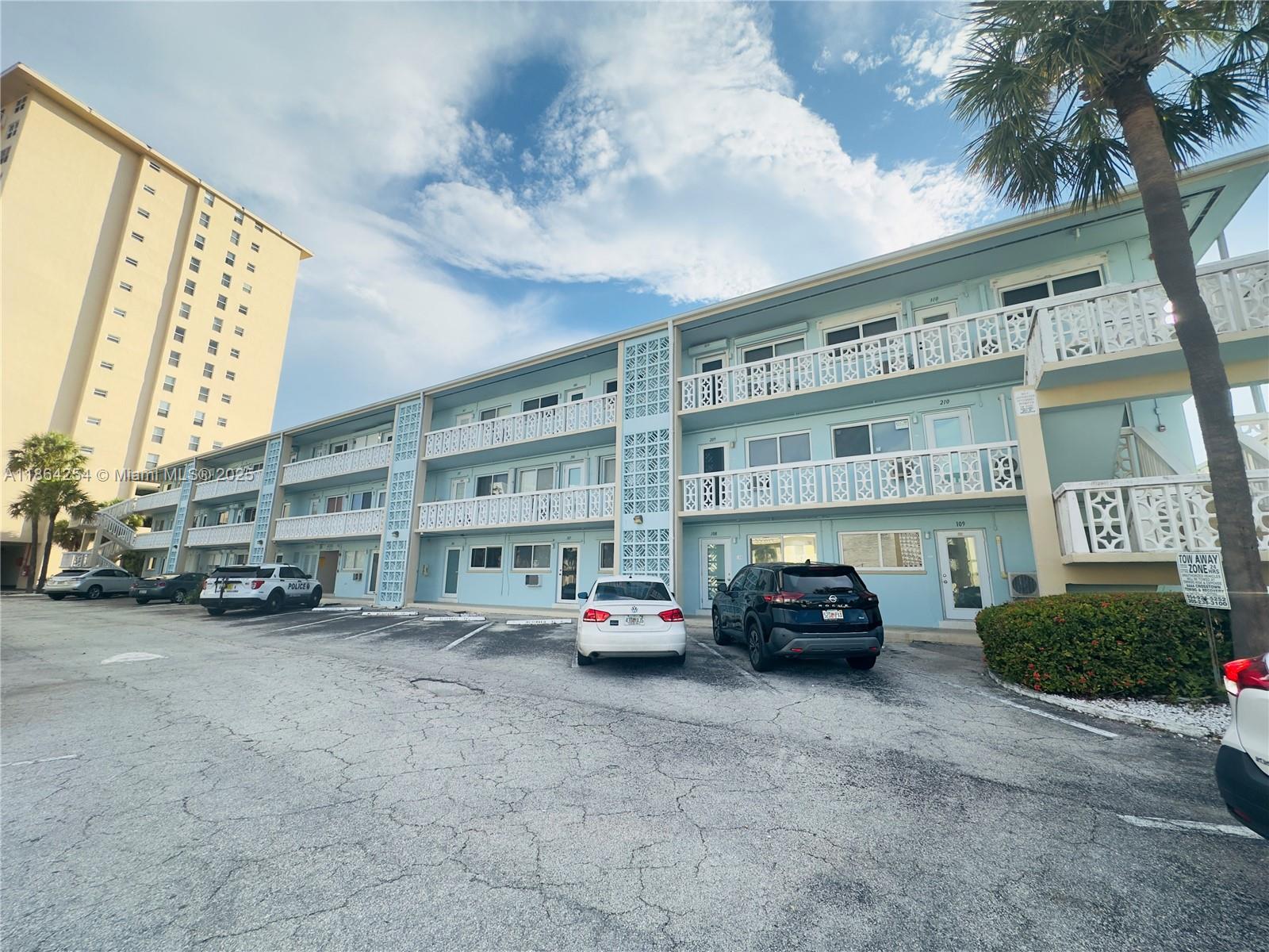 455 Golden Isles Drive, Unit 210 Hallandale Beach, FL 33009 - Photo 25 of 27 a view of building with cars parked in front of it