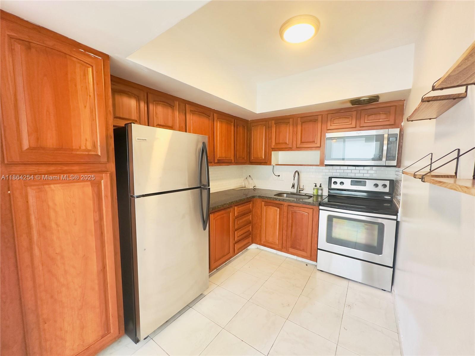 455 Golden Isles Drive, Unit 210 Hallandale Beach, FL 33009 - Photo 7 of 27 a kitchen with granite countertop stainless steel appliances and refrigerator