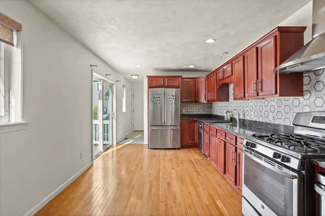 a kitchen with stainless steel appliances hardwood floor sink stove and wooden cabinets