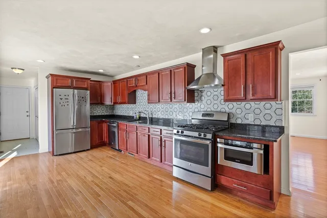 a kitchen with stainless steel appliances granite countertop a stove cabinets and wooden floor