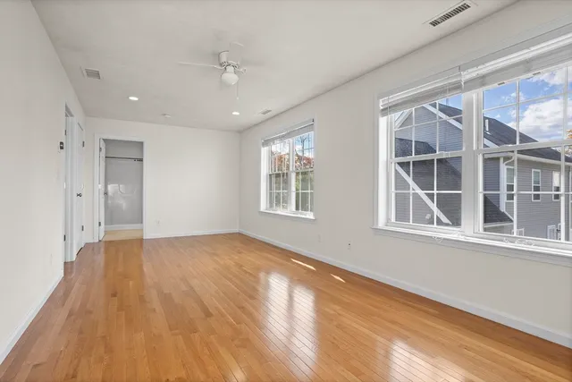 a view of an empty room with a window and wooden floor